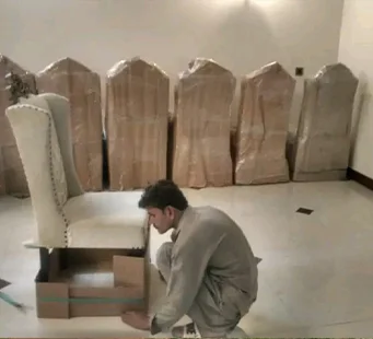 Crew hand-wrapping furniture before transit